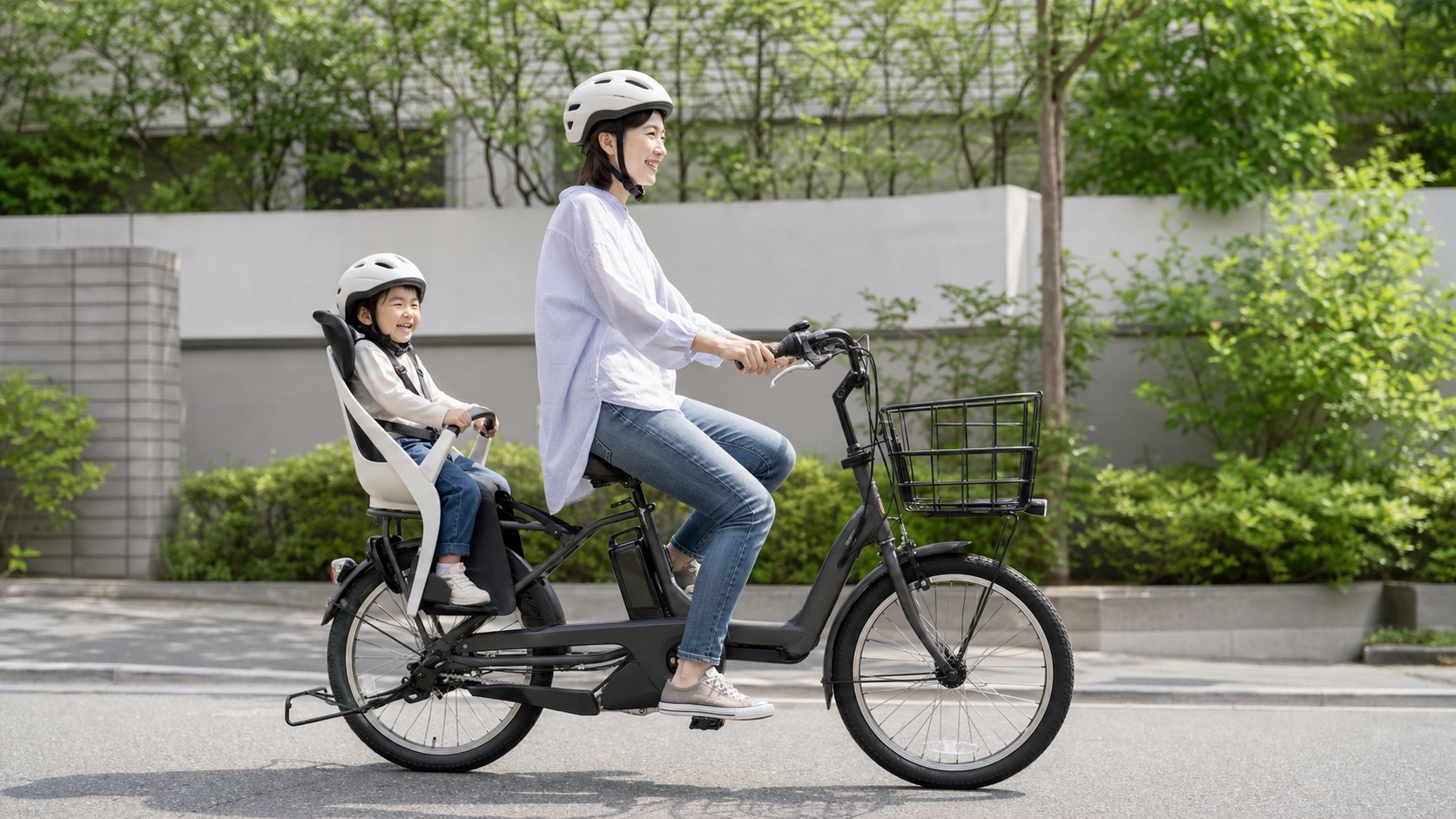 親子がヘルメットを着用して電動アシスト自転車とチャイルドシートで移動する様子