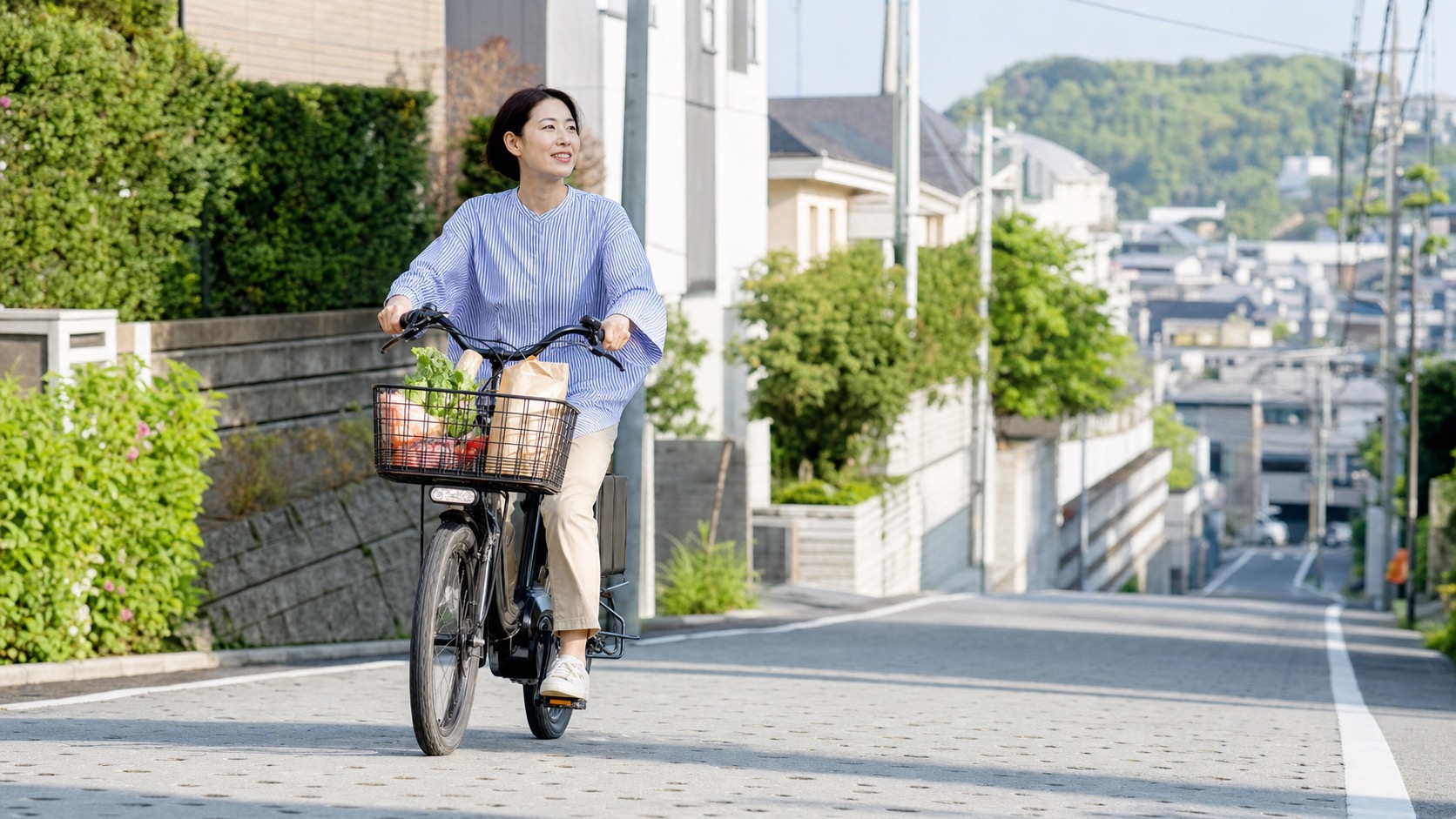 坂道でも買い物をしながら快適に走る電動アシスト自転車のイメージ